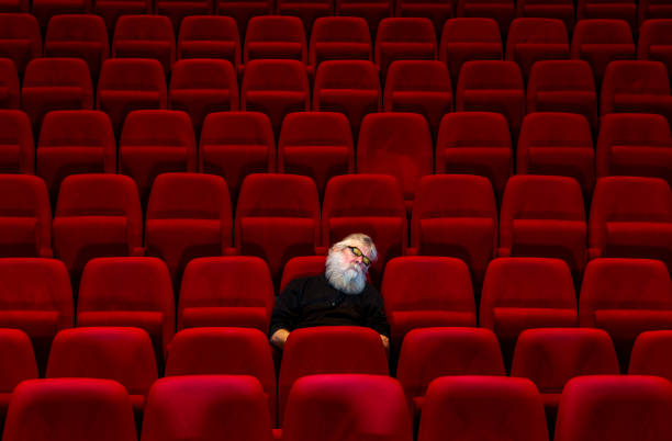 istock One man with white beard sits in Empty cinema or theatre with comfortable red seats, sleeping 1262313113