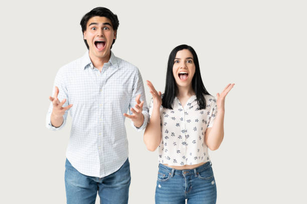 Surprised Young Couple Screaming In Studio Astonished Hispanic boyfriend and girlfriend with mouth wide open unusual couple stock pictures, royalty-free photos & images