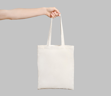 Male hand holding eco bag isolated on white background.