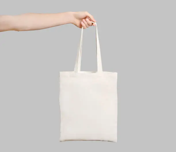 Male hand holding eco bag isolated on white background.