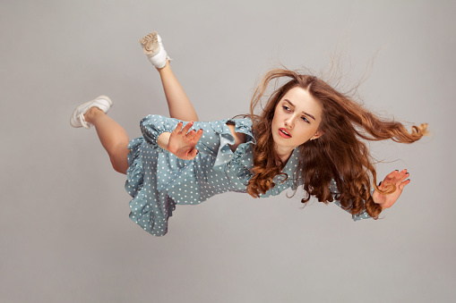 Hermosa chica levitando en el aire, cayendo y su cabello estropeado volando del viento, modelo volando flotando con expresión pacífica de ensueño. photo