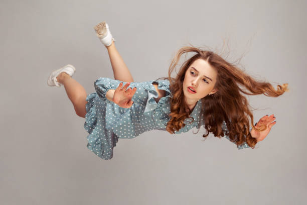 hermosa chica levitando en el aire, cayendo y su cabello estropeado volando del viento, modelo volando flotando con expresión pacífica de ensueño. - levitación fotografías e imágenes de stock