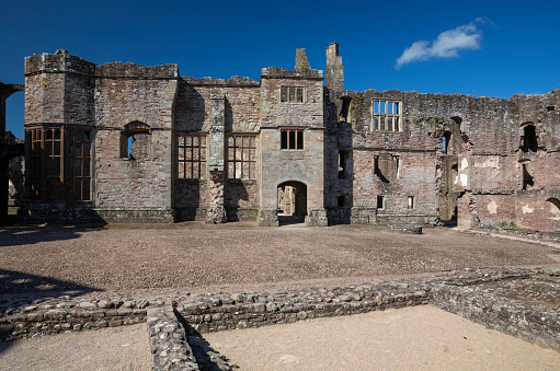 Raglan Castle is a late medieval castle located just north of the village of Raglan in Monmouthshire, South East Wales. The modern castle dates from between the 15th and early 17th centuries.\nSurrounded by parkland, water gardens and terraces, the castle was considered by contemporaries to be the equal of any other castle in England or Wales.