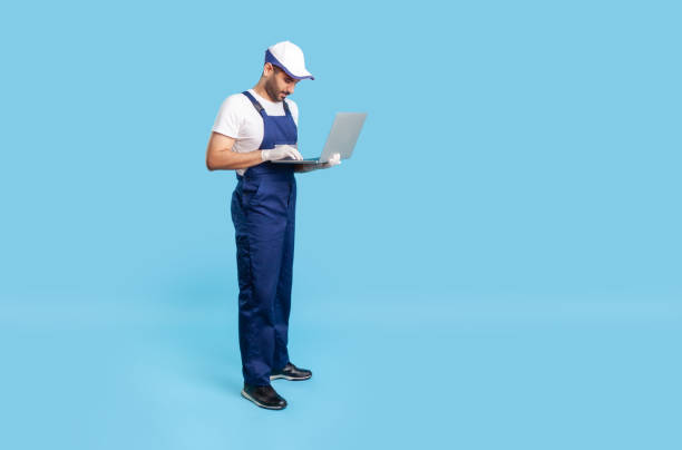 istock Full length professional workman in uniform and protective gloves typing on laptop keyboard, online communication 1262317672