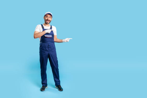 istock Full length surprised handyman in uniform pointing at copy space, advertising area for idea presentation 1262317720