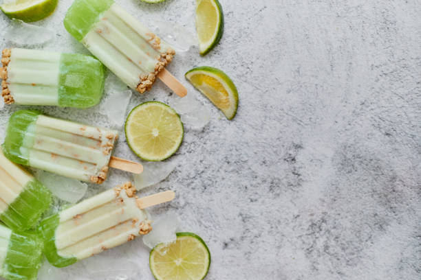 istock Lime and cream homemade popsicles or ice creams placed with ice cubes on gray stone backdrop 1262319030