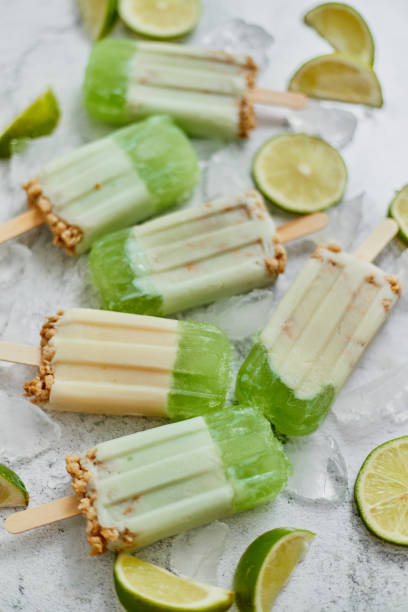 istock Lime and cream homemade popsicles or ice creams placed with ice cubes on gray stone backdrop 1262319045