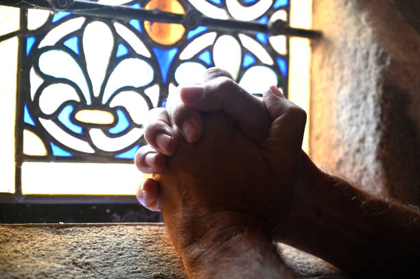 Mature hispanic woman praying at church window