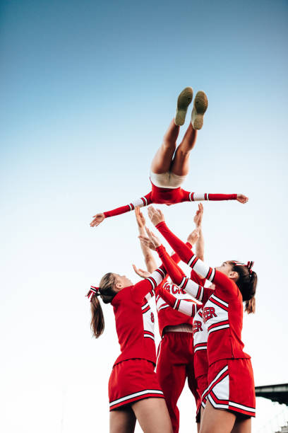 cheerleader throw-up-mädchen in der luft - arms outstretched teenage girls jumping flying stock-fotos und bilder