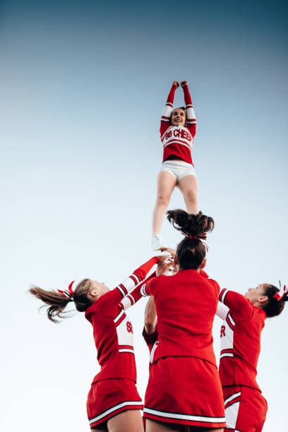 cheerleader throw-up-mädchen in der luft - arms outstretched teenage girls jumping flying stock-fotos und bilder