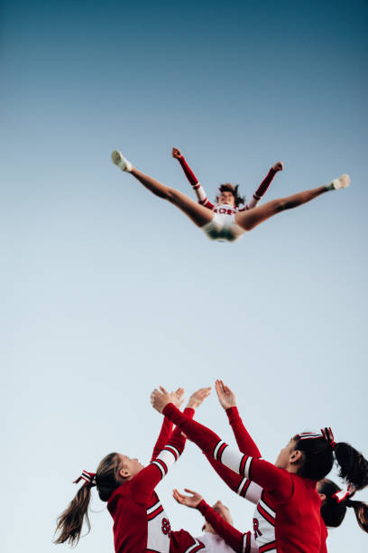 cheerleader throw-up-mädchen in der luft - arms outstretched teenage girls jumping flying stock-fotos und bilder