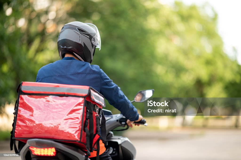 The staff prepares the delivery box on the motorcycle for delivery to customers. Delivery Person Stock Photo