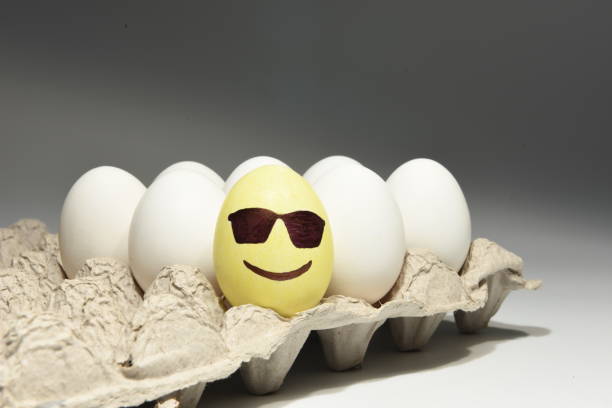 Cool smiley face with sunglasses on an eggshell Illustrated smiling face with sunglasses on a yellow colored eggshell along with white eggs in an egg tray sabby stock pictures, royalty-free photos & images