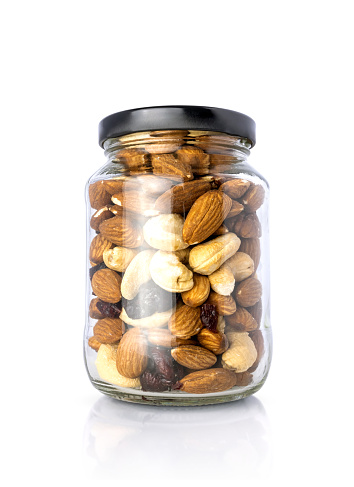 Clear glass bottle with mixed nuts healthy organic food isolated on white background with clipping path