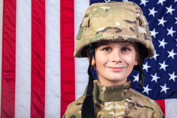 アメリカ国旗を持つ兵士のような服を着た少年 - child military saluting flag ストックフォトと画像