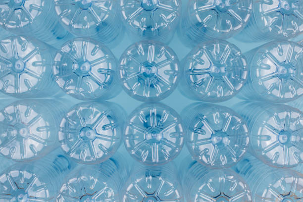 istock Empty clear plastic bottles without caps stacked on a blue background. Recycling and environment concept. 1262343061