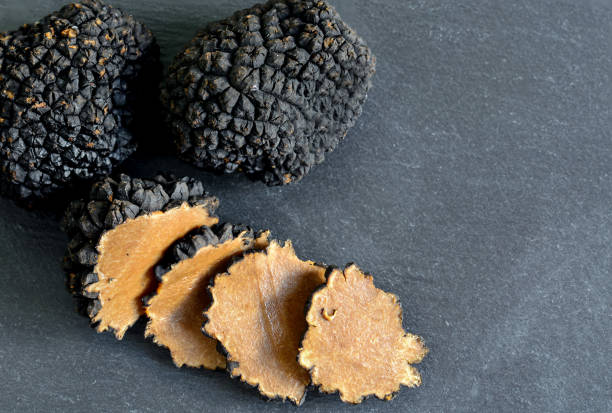 istock Black truffles and slices on black stone background 1262350365