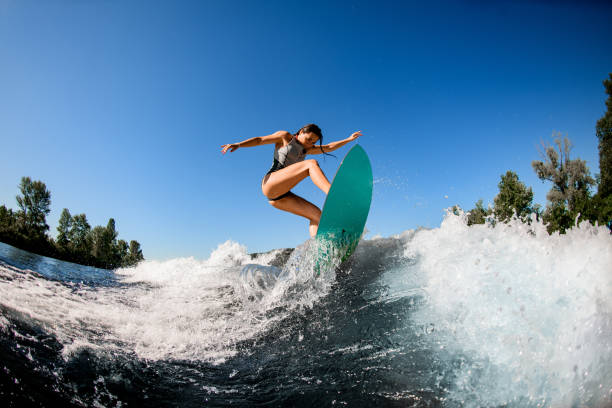 istock young wet woman energetically balancing on wave on wakesurf board 1262354103