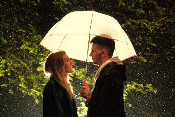 istock Young couple standing under the umbrella, on a rainy night 1262356426