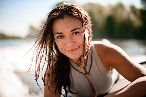 Portrait of young beautiful smiling woman with brown eyes and wet hair on blurred background beach