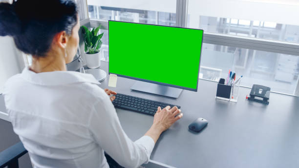 istock In Open Space Office Businesswoman Working on Her Personal computer with Green Mock-up Screen. Shot in Big Bright Modern Open Space Office. 1262359073