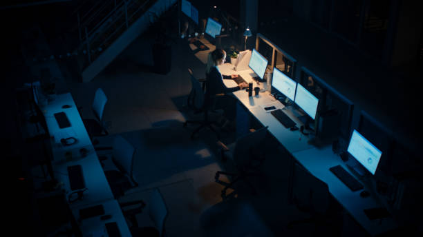 istock Working Late at Night in the Office: Businesswoman Using Desktop Computer, Having Discussion, Analyzing, Using Documents, Solving Problems, Finishing Project. High Angle Shot 1262359159