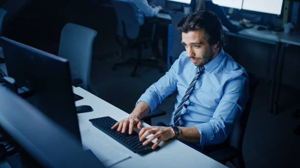 istock In the Office at Night Overworked Tired Office Worker Uses Desktop Computer Yawning. Tired Exhausted Businessman Finishing Important Project 1262359349