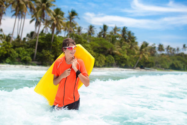 istock Child surfing on tropical beach. Surfer in ocean. 1262360282