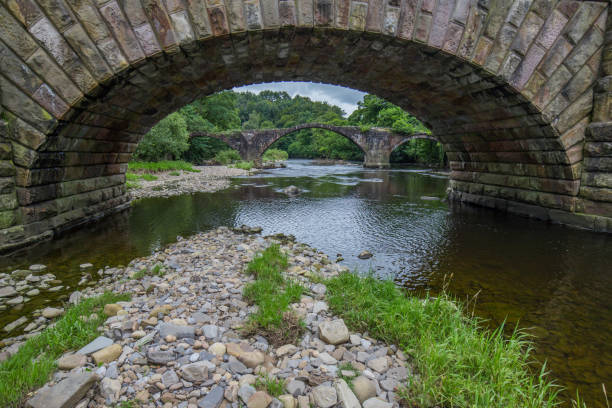 ponte cromwells em ribble valley, lancashire. velha ponte de pedra sobre o rio hodder disparou através de um arco da ponte hodder mais nova. - ribble - fotografias e filmes do acervo