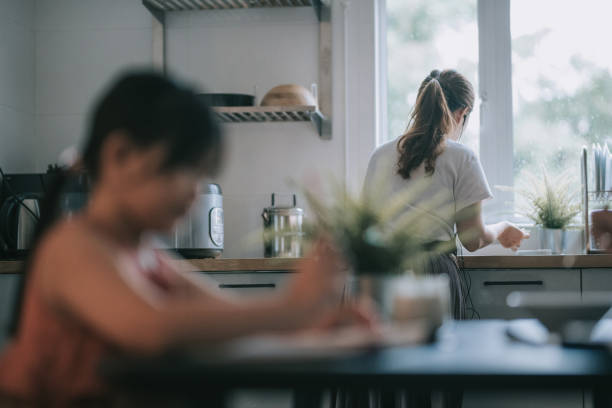 istock one daughter studying at home writing Chinese calligraphy in dining room while her mother preparing food in the kitchen 1262360393