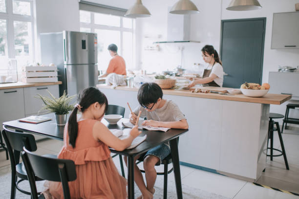 istock 2 young children studying at home writing Chinese calligraphy in dining room while their mother cooking preparing food 1262360504