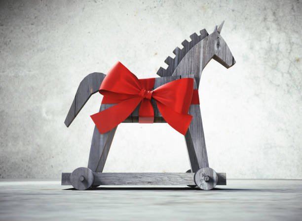 Trojan Horse as a Gift Trojan horse with red satin bow as symbol for computer virus with stone background trojan horse stock pictures, royalty-free photos & images