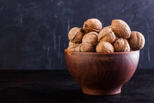istock Full clay bowl with walnut on a dark background. Copy space. 1262371538