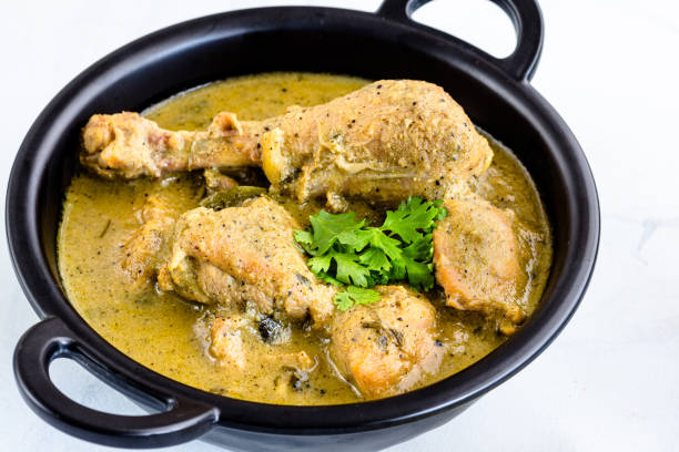 istock Spicy Indian Black Pepper Chicken on White Background Garnished with Cilantro and Lemon 1262371881