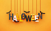 Halloween Written by Hanging Letters and Flying Bats over Orange Background