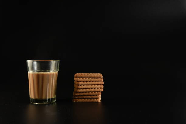 Chai (Indian tea) and biscuits A shot of hot chai (Indian tea) in a half-glass along with glucose biscuits sabby stock pictures, royalty-free photos & images