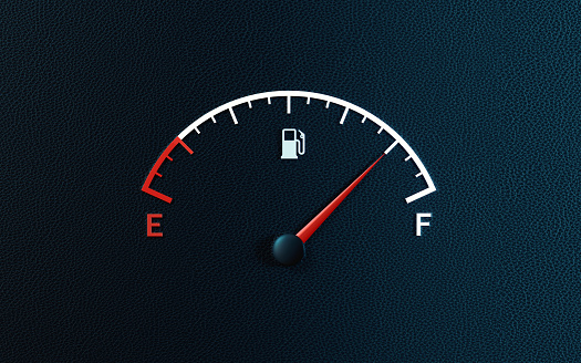 Fuel gauge's red needle indicating full gas tank on black background. Horizontal composition with copy space.