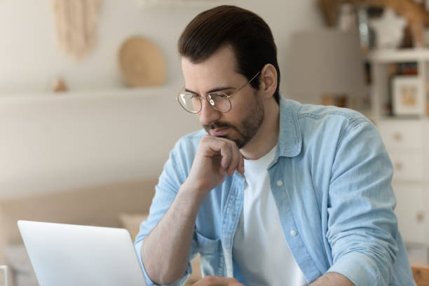 istock Pensive Caucasian man look at laptop screen working on gadget 1262376577
