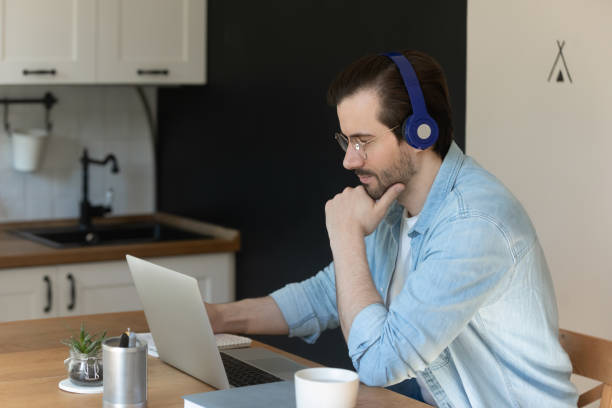 istock Millennial man in headphones watch webinar on laptop 1262376607