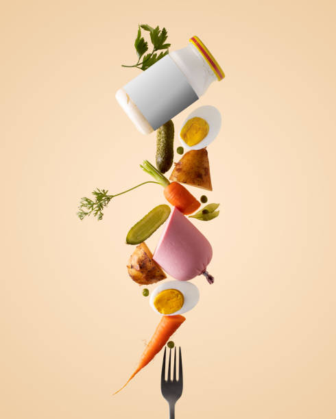 Balancing stack of fresh raw ingredients for making russian soviet salad on a beige background, mockup mayonnaise jar