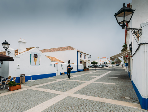 Porto Covo, Alentejo, Portugal - July 18, 2020: Main square with people relaxing at cafes in pictureque Porto Covo in Portugal