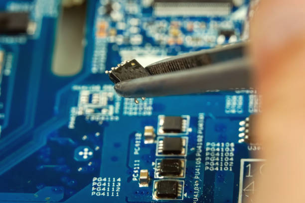 Master tweezers takes a microchip from the laptop's motherboard close up