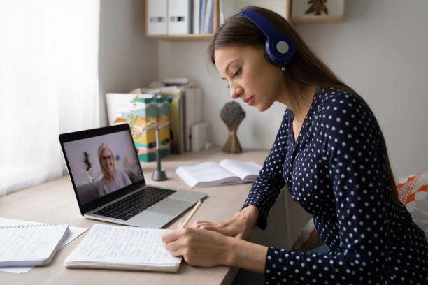 istock Female in headphones make notes studying on laptop 1262378635