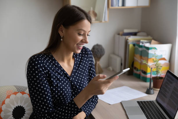 istock Smiling Caucasian girl sit at desk using modern cellphone 1262378677