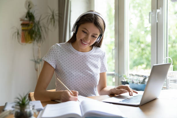 istock Smiling girl in headphones study online using laptop 1262378761