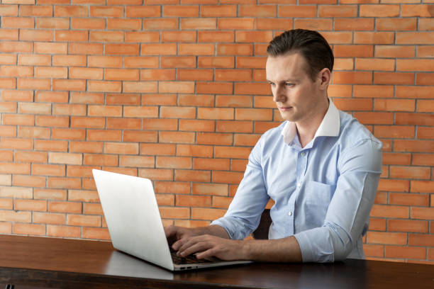 istock Focused business man working on laptop at cafe with brick wall background 1262381549