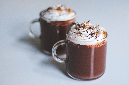 Two luxury hot chocolates in glass mugs with cream, nutmeg  and chocolate shavings
