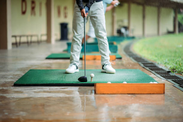Close up of asian chinese senior man golfer getting ready tee off before swing his golf club at golf driving range stock photo
