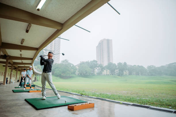 golfeur chinois asiatique d’homme aîné teeing au loin et balancer son club de golf au secteur de conduite de golf - golf golf swing putting cheerful photos et images de collection