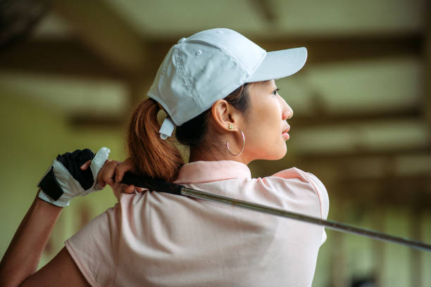 fermez-vous vers le haut de la jeune golfeuse asiatique balancent son conducteur au secteur de conduite de golf - freedom tire swing tire swing photos et images de collection